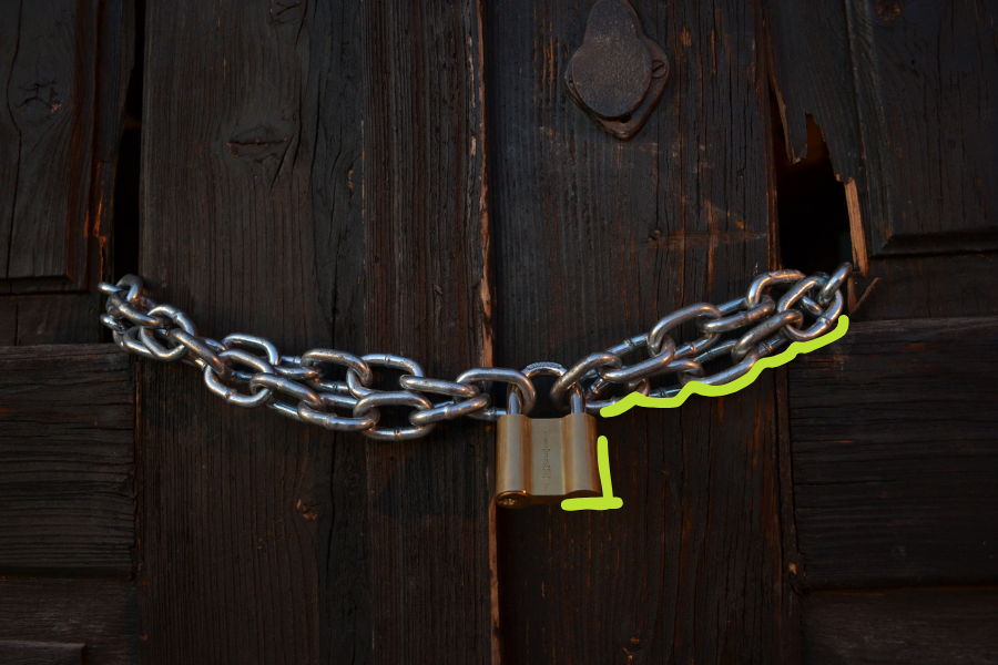 Padlock with a chain on a dark wooden door, with green hand-drawn marks on the chain and under the lock, a symbol for missing authority and for ownership