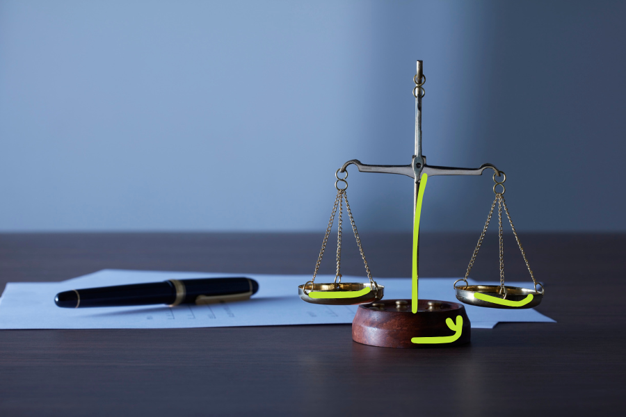Messingwaage auf einem Holzsockel vor blauem Hintergrund, daneben ein Füller auf einem Blatt Papier, dazu grüne Handzeichnungen an Waagschalen und Sockel, Sinnbild für ungeregelten Spielraum und für Ownership